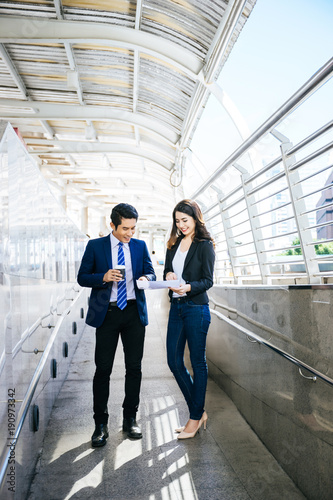 Business colleagues take a look at the work in the tablet while walking to the office together.