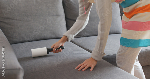 Woman cleaning sofa with sticky roller