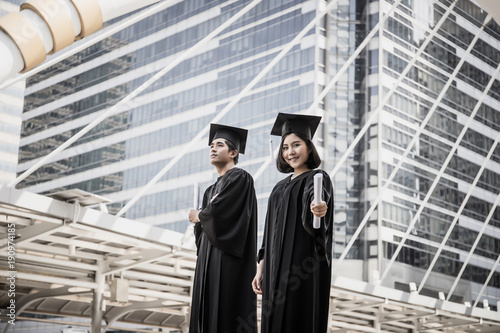 Happy international students and bachelor gowns with diplomas.