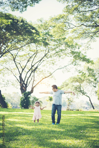 Toddler girl holding hands with her father in the park, happiness time.