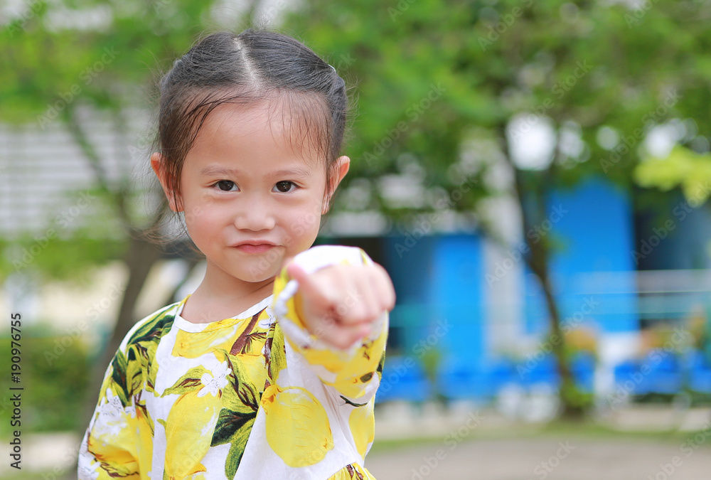 Cute smiling little girl pointing at camera in the garden. Cute smiling little girl pointing at camera in the garden.