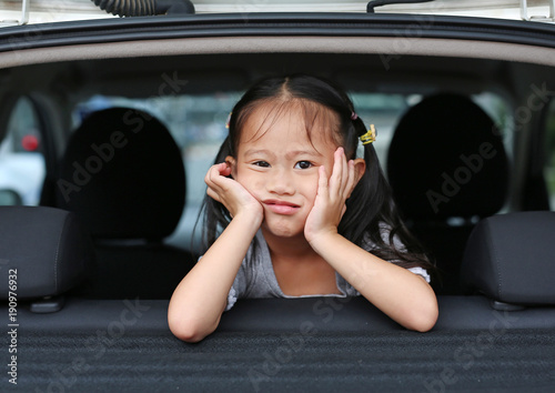 Funny face little asian child looking camera from the window of the car. © zilvergolf