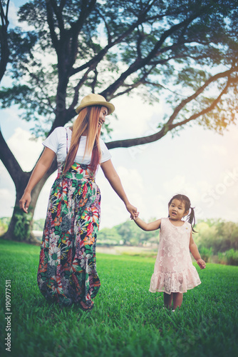 Young mother and her little daughter walking in ther park © Johnstocker