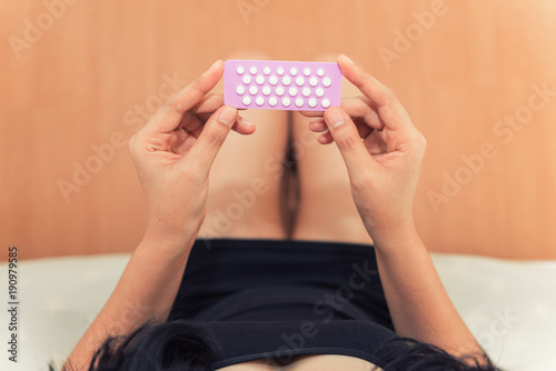 Asian woman holding contraceptive pills in the bed room, Health and medical concept