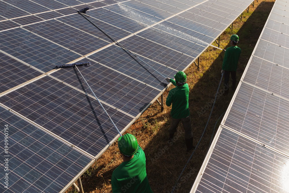 labor working on cleaning solar panel at solar power plant; operation ...