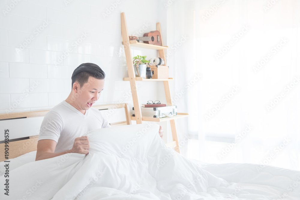 Asian man looking under blanket with excited face Asian man looking under blanket with excited face