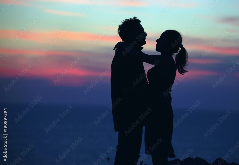 Silhouette of a loving couple against the sky after sunset