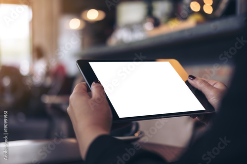Mockup image of a woman holding black tablet pc with blank white desktop screen in cafe