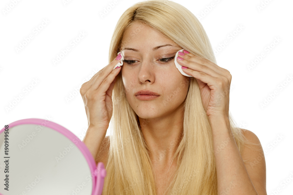 young woman cleaning her face with cotton pad osn white background young woman cleaning her face with cotton pad osn white background