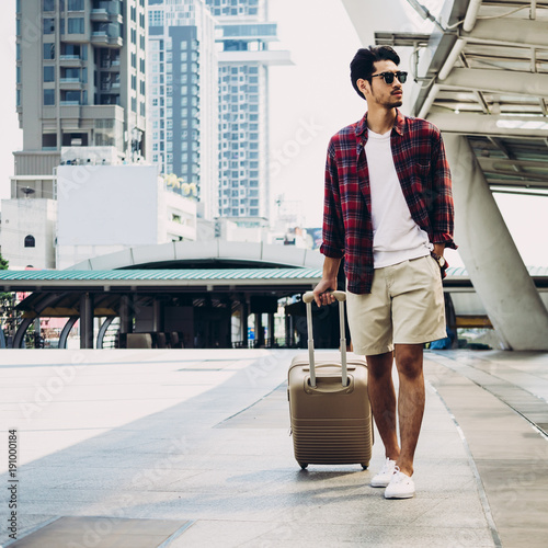 Young Asian tourist with luggage walking  and enjoying vacations on city street. Travel concept