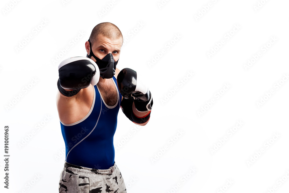 Young sportive man in blue tights,black elbow, black and white boxing gloves and training mask boxing on a white isolated background Young sportive man in blue tights,black elbow, black and white boxing gloves and training mask boxing on a white isolated background