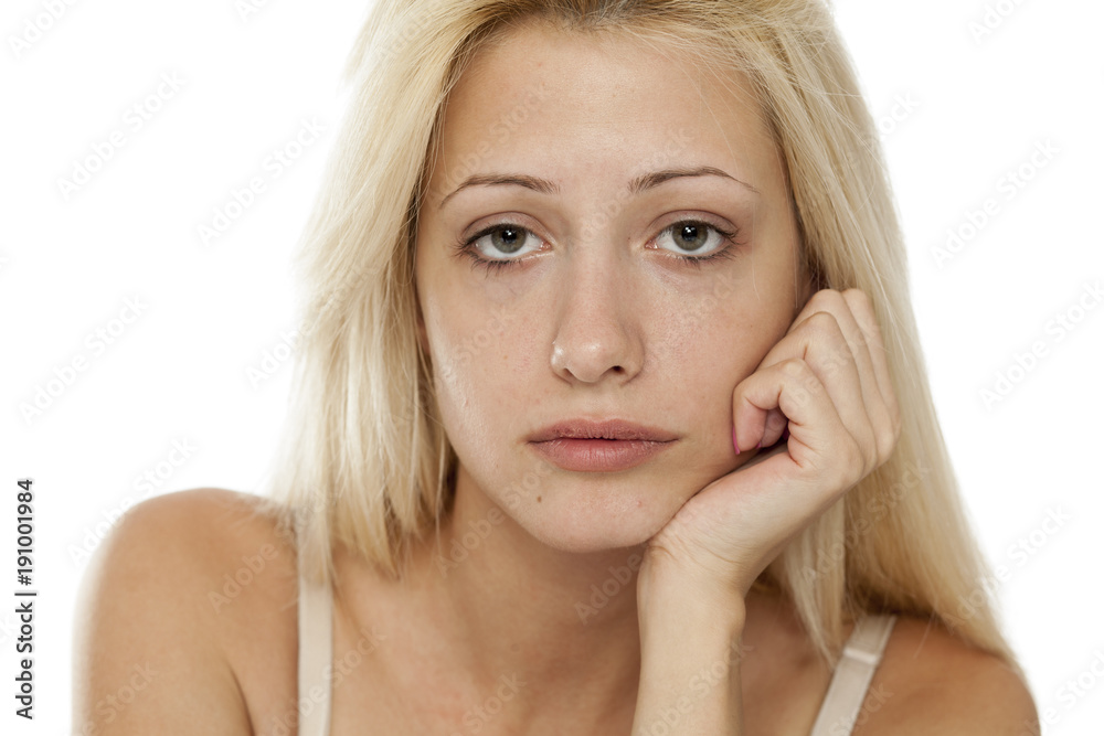 Young blonde sad woman without makeup on white background Young blonde sad woman without makeup on white background