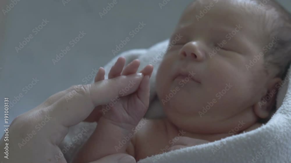 Adorable newborn baby sleeping and holding his mother's hand
