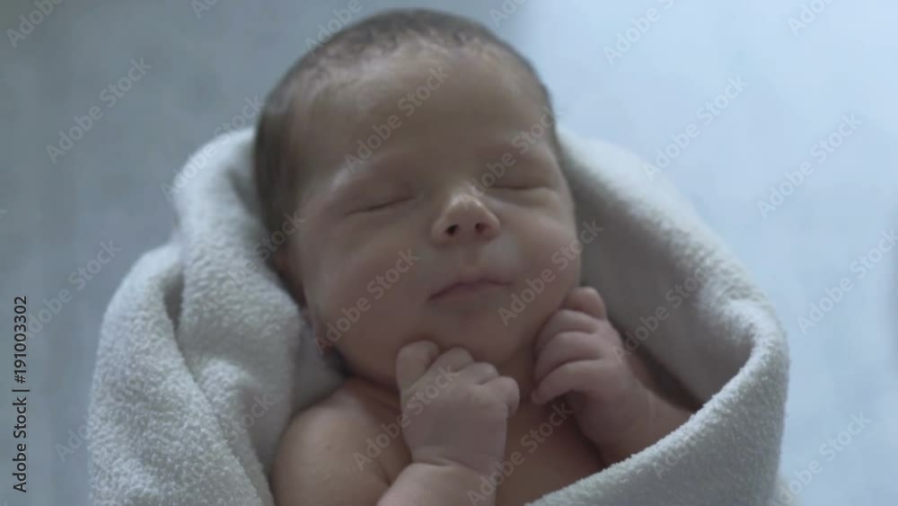 Adorable newborn baby sleeping in a blanket and holds his mother's hand
Adorable newborn baby sleeping in a blanket and holds his mother's hand