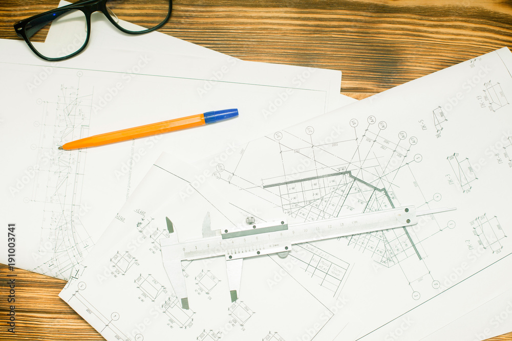 Construction plans, pen and glasses on wooden board background, top view, closeup Construction plans, pen and glasses on wooden board background, top view, closeup
