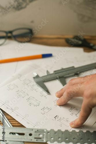 Construction plans, pen and measure tools on wooden board background, top view, closeup