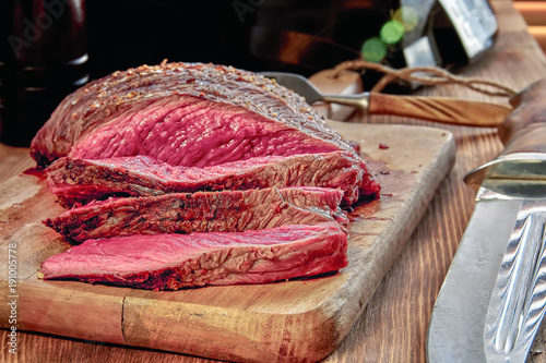 Roasted meat with blood. Well-Done Steak closeup. Wooden background.