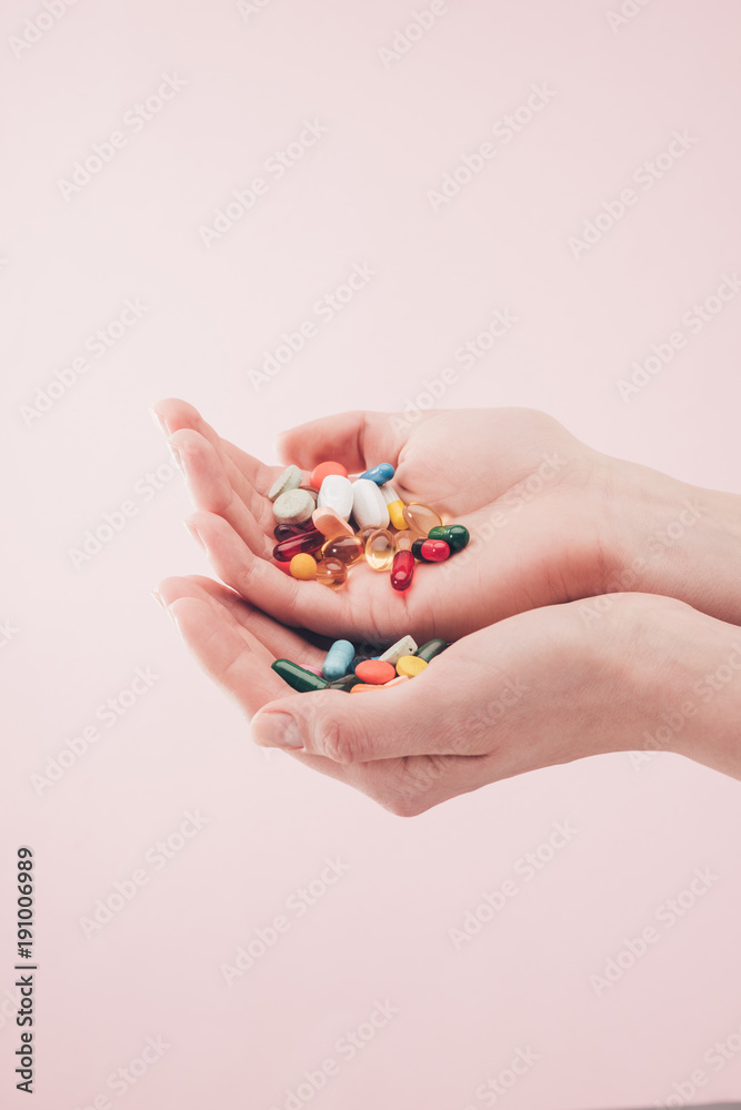 partial view of woman holding pills in hands isolated on pink