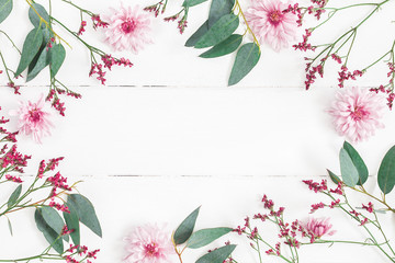 Flowers composition. Frame made of pink flowers and eucalyptus branches on white wooden background. Flat lay, top view, copy space