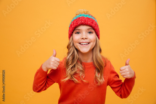 Happy Young girl in sweater and hat showing thumbs up © Drobot Dean