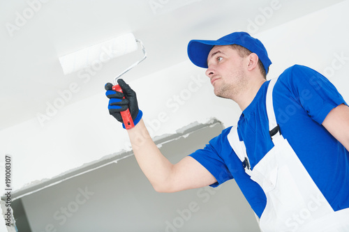 Painter painting ceiling with paint roller