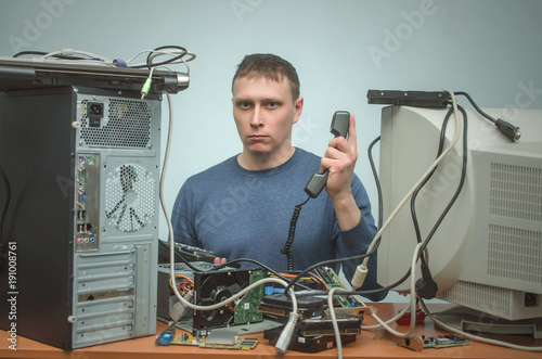 Serious Computer technician is consulting a users by their questions by the phone. PC repair service center.