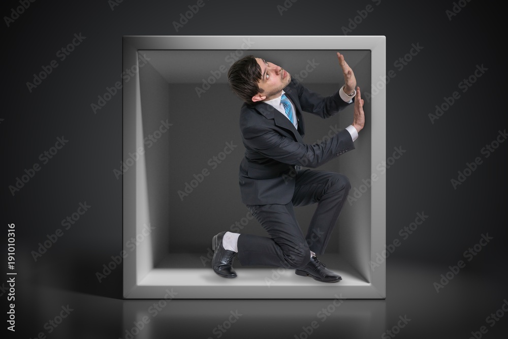Fotografie Young businessman trapped inside uncomfortable small box.