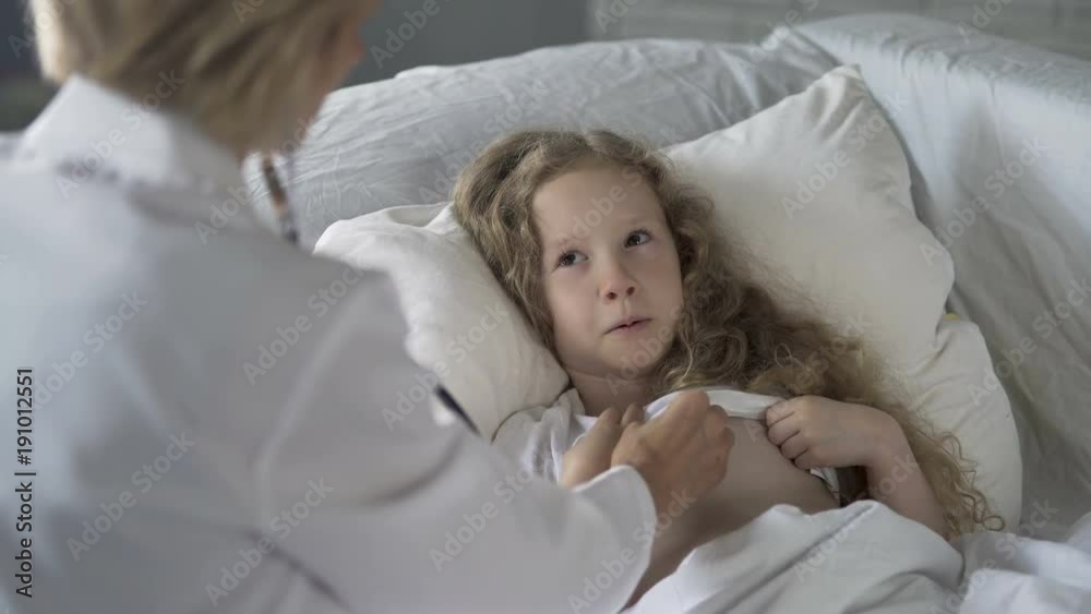 Woman doctor carefully examining sick child with stethoscope, little girl crying