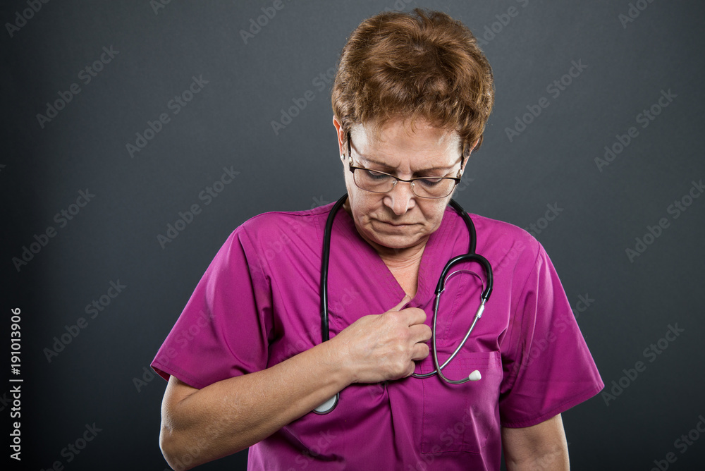 Portrait of senior lady doctor holding chest like having pain Portrait of senior lady doctor holding chest like having pain