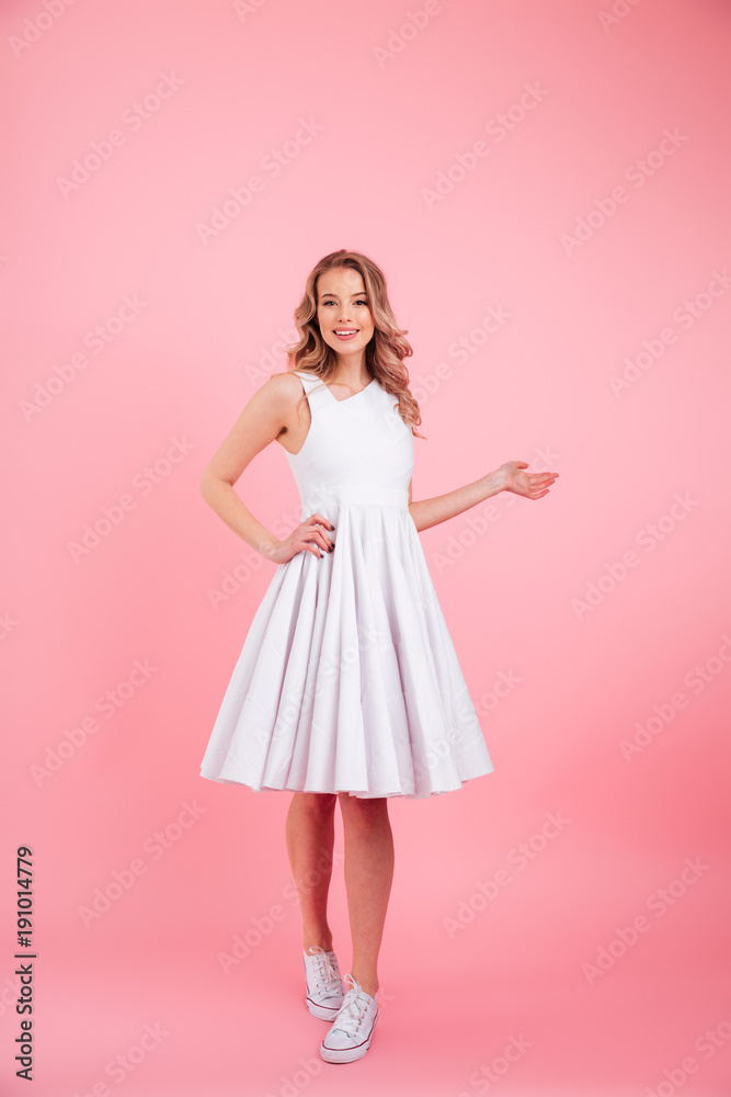 Full-length photo of charming blonde woman looking on camera with smile and holding copyspace on her palm, isolated over pink background Full-length photo of charming blonde woman looking on camera with smile and holding copyspace on her palm, isolated over pink background