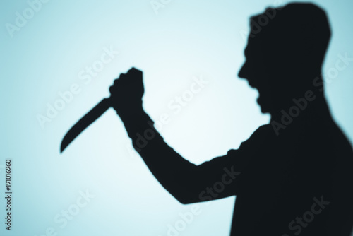 shadow of person screaming and holding knife on blue