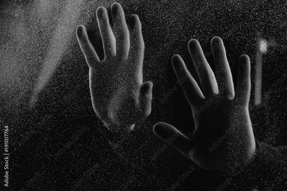 cropped shot of person touching frosted glass with palms in darkness cropped shot of person touching frosted glass with palms in darkness
