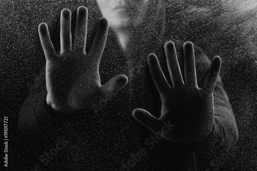 cropped shot of person touching frosted glass in darkness