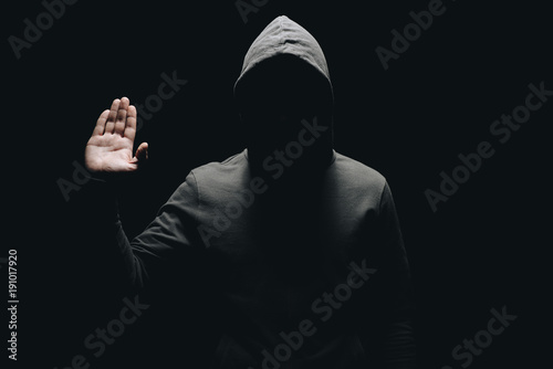 unrecognizable man in hoodie showing palm isolated on black
