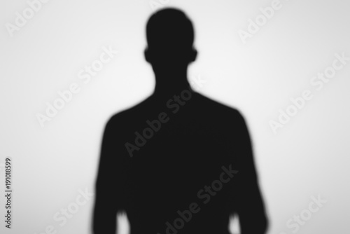 mysterious blurry shadow of spooky person standing on grey