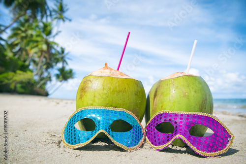 Colorful sequined carnival masks and fresh green coconut drinks on a palm fringed beach in Brazil