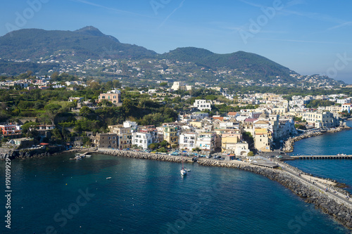 Scenic overlook view of the waterfront village of Ischia Ponte with the volcanic mountains towering above the horizon on the Mediterranean island of Ischia, Italy © lazyllama