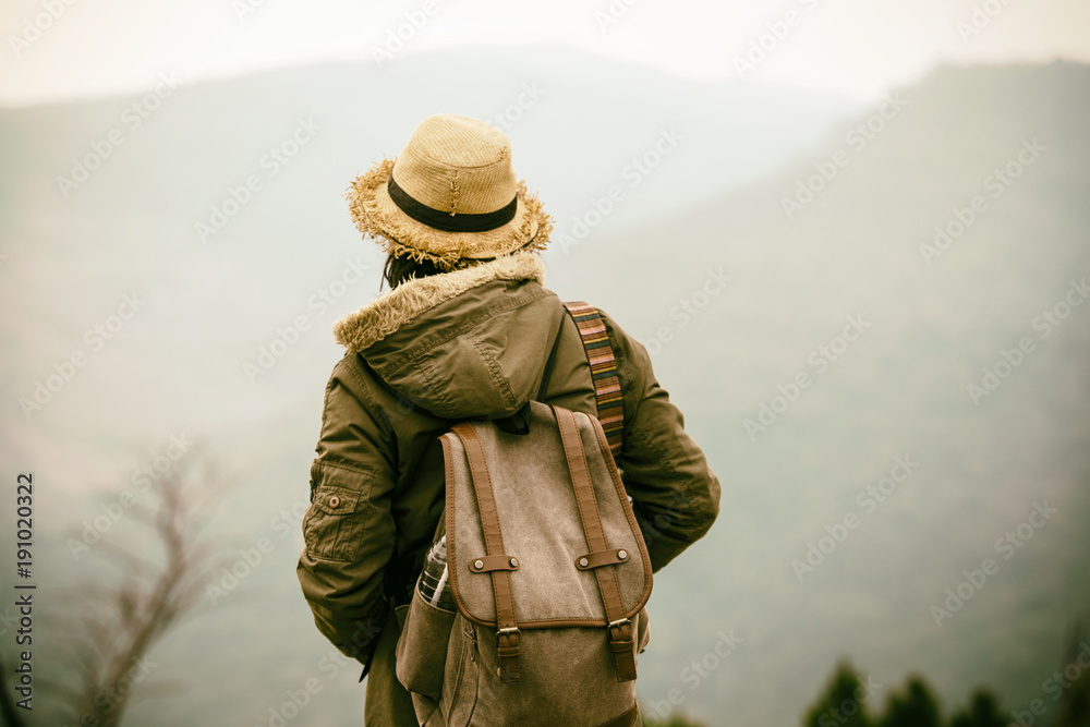 Young Hipster woman traveling in mountain with backpack enjoying sunrise