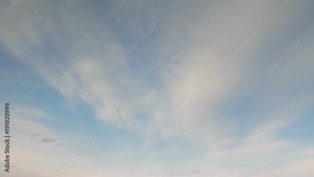 Russia, time lapse. Formation and rapid movement of white clouds of different shapes in the blue sky in late spring at sunset.