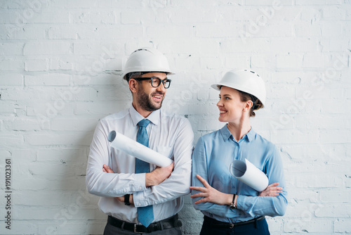 architects in hard hats standing in front of white brick wall with blueprints photo