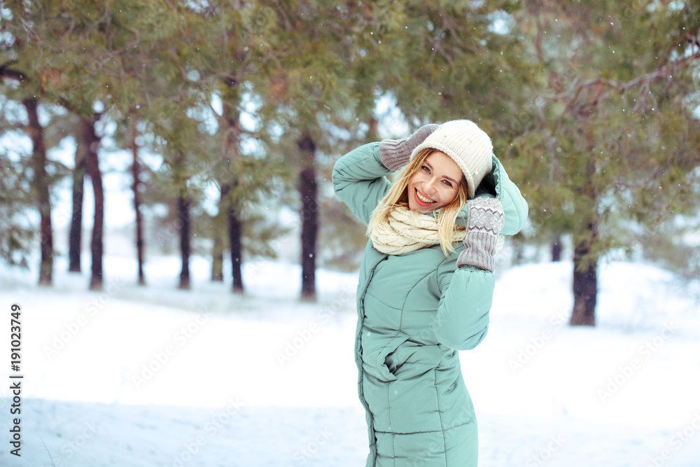 Young beautiful happy blonde girl outdoors in winter looking at camera and smiling. Winter. A girl is walking in the winter forest. Portrait. Space for text close-up. Young beautiful happy blonde girl outdoors in winter looking at camera and smiling. Winter. A girl is walking in the winter forest. Portrait. Space for text close-up.
