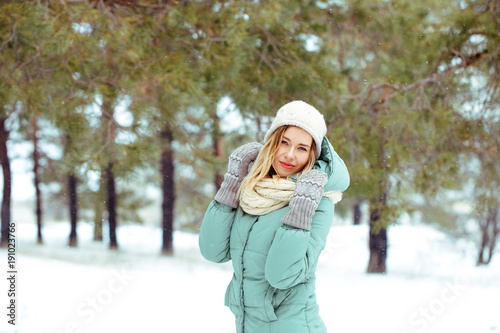 Young beautiful happy blonde girl outdoors in winter looking at camera and smiling. Winter. A girl is walking in the winter forest. Portrait. Space for text close-up.