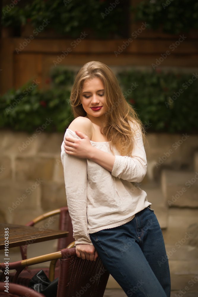 Romantic young woman with red lips, wearing trendy outfit, posing at the street in Lvov
