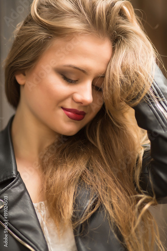 Closeup shot of attractive young woman with red lips and lush blonde hair posing with closed eyes