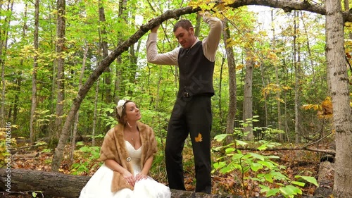 married couple pose under bent over tree for photoshoot in woods 4k photo