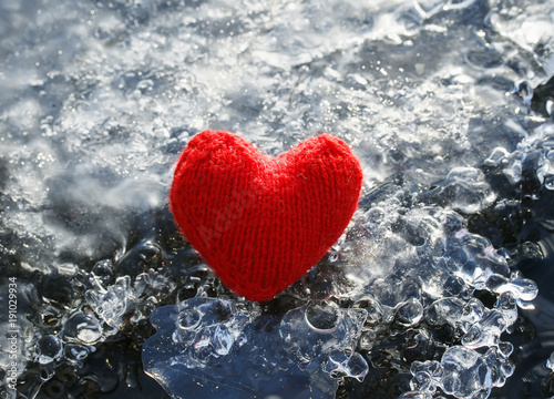 red knitted heart lying on the cold glittering ice