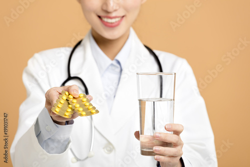 smiling female doctor giving pills and clean water.