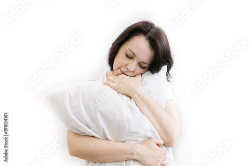Young woman sitting on bed, hugging pillow, smiling. on white background. a girl can't Wake up