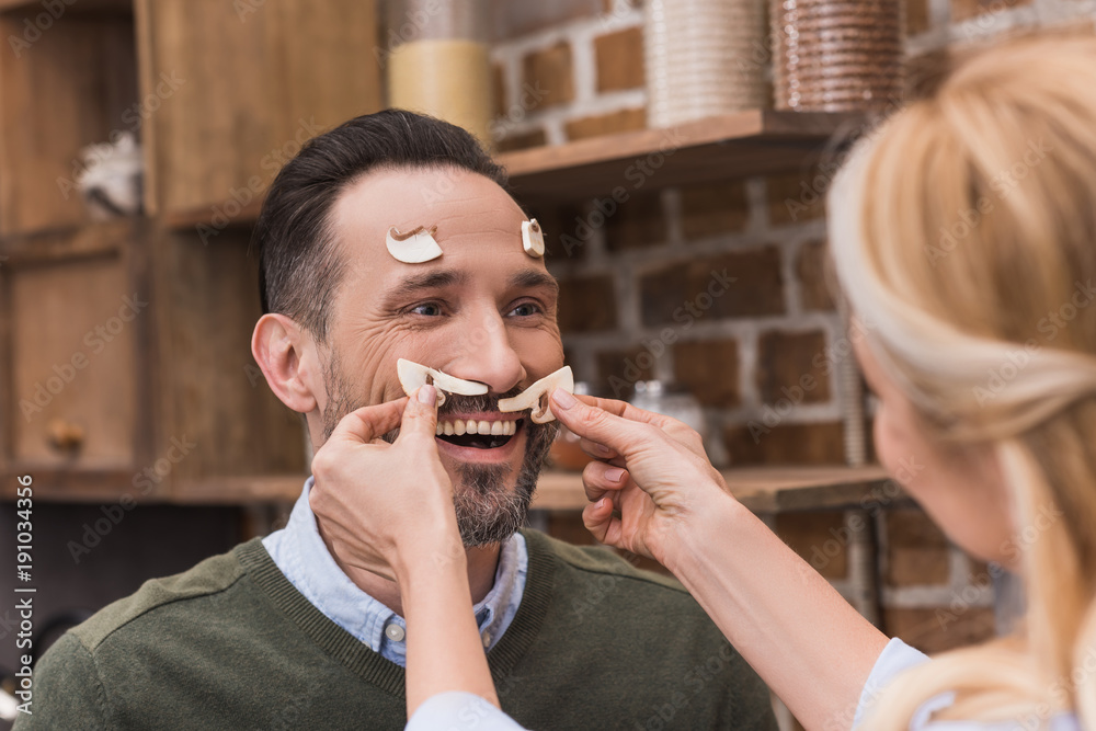 wife putting pieces of mushrooms on husband face