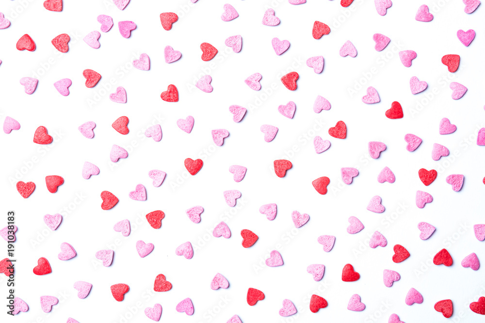 Red and pink sugar hearts on white forming a cute background for St.Valentine’s Day.
